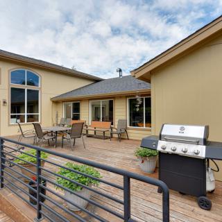 A spacious outdoor patio with a grill and seating area on a wooden deck.