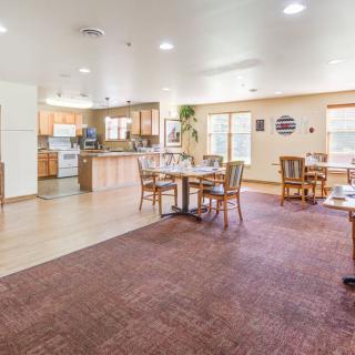 A spacious dining area with tables and chairs adjacent to a well-lit kitchen.