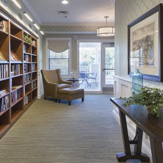 A cozy library interior featuring bookshelves, a reading chair, and ample natural light.