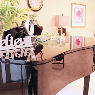 A beautifully arranged living room featuring a glossy piano and tasteful decorations.
