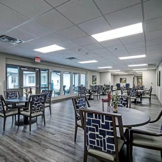 A modern dining area with neatly arranged tables and chairs, illuminated by bright ceiling lights.