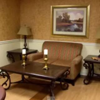 A cozy living room with a couch, tables, lamps, and a landscape painting.