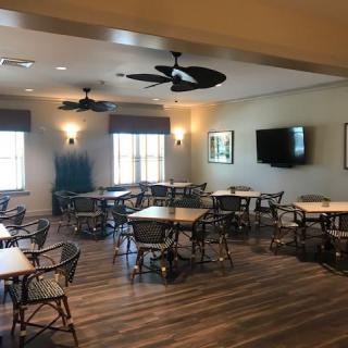 A dining area with multiple tables and chairs, featuring ceiling fans and a television.