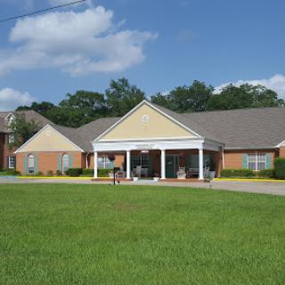 A serene residential building surrounded by lush green grass under a partly cloudy sky.