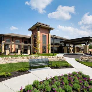 A modern building set amidst a beautifully landscaped garden with vibrant flowers and a clear blue sky.