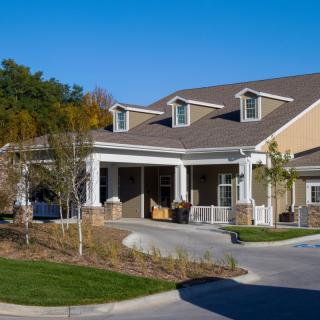 A suburban house with a porch and driveway on a sunny day.