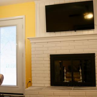 A cozy living room setup with a white brick fireplace and a mounted television.