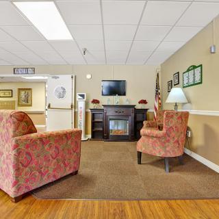 A cozy lobby area with patterned armchairs, a television, and a decorative fireplace.
