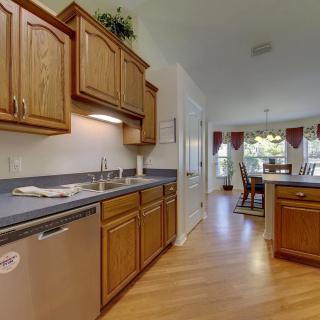 A spacious kitchen with wooden cabinets and a view into the dining area.