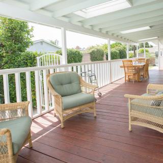 A cozy porch with wicker furniture and cushioned chairs, perfect for relaxing outdoors.