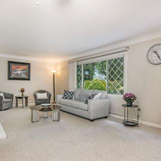 A cozy living room with a sofa, chairs, and a large window overlooking greenery.