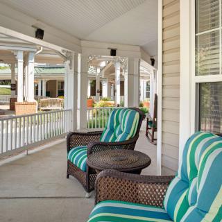 A cozy porch area with striped cushioned chairs overlooking a series of columns.