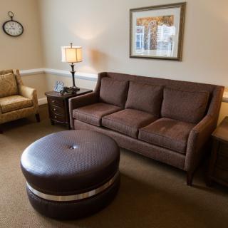 A cozy living room with a brown sofa, armchair, ottoman, and decorative elements.