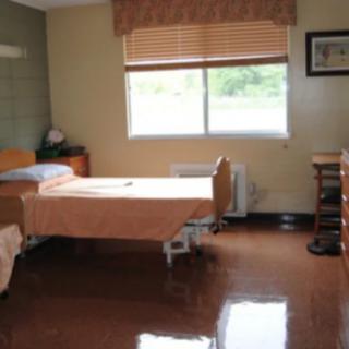 A hospital room with two beds and a large window covered by curtains.