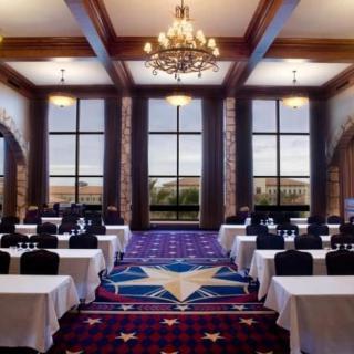 A spacious conference room with elegant chandeliers and large windows, set up for a meeting.