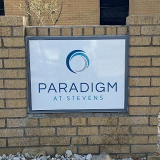 Signage for Paradigm at Stevens displayed on a brick wall.