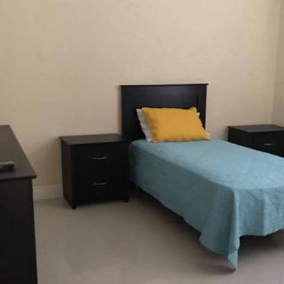 A minimalist bedroom with a single bed and matching furniture.