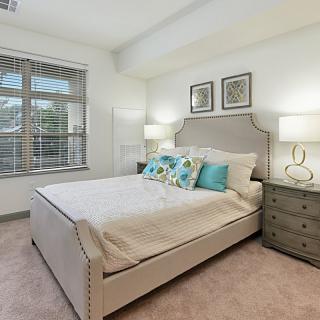 A cozy bedroom with modern decor featuring a plush bed, decorative pillows, and bedside lamps.