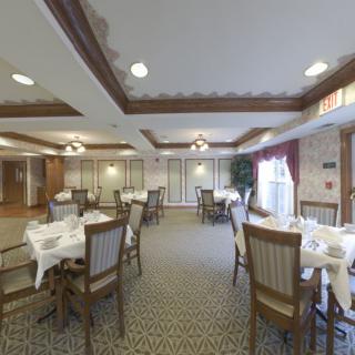 An elegant dining room with neatly arranged tables and chairs, featuring tasteful decor and lighting.
