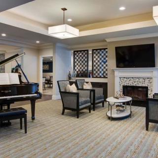 A modern living room featuring a grand piano, comfortable seating, and a fireplace.