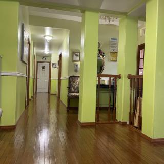 A well-lit hallway with green walls and a polished wooden floor.