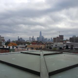 A view of the city skyline from a rooftop, under a cloudy sky.