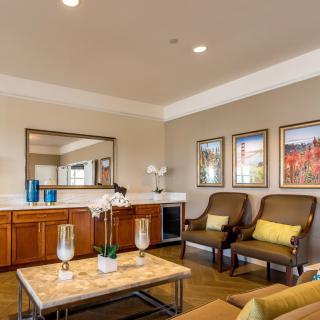 A well-decorated living room featuring elegant chairs, a coffee table with decorative items, and framed artwork on the walls.