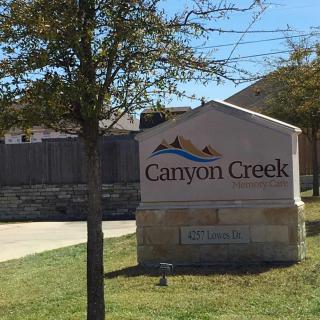 Entrance sign for the Canyon Creek neighborhood surrounded by trees and grass.