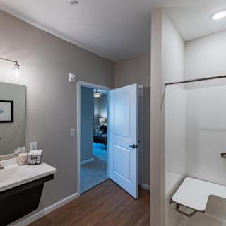 A modern bathroom featuring a sleek sink and shower, with an inviting door leading to another room.