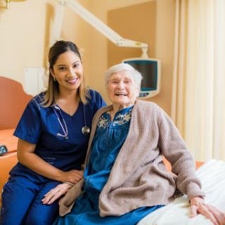 A compassionate nurse posing with an elderly patient in a hospital setting, highlighting the caring relationship in healthcare.