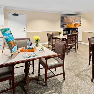 A cozy dining area with art supplies set up on the tables, featuring comfortable chairs and a television.