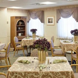 A well-decorated dining room with multiple tables, each adorned with floral centerpieces and elegant table settings.