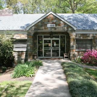 A small brick house with a well-maintained garden and pathway leading to the entrance.