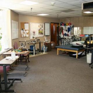 A physical therapy clinic with various exercise equipment and therapy tables.