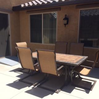 Outdoor patio set with chairs and a table in a backyard setting.