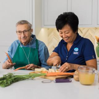 Two people preparing food together in a kitchen, focusing on cutting carrots.