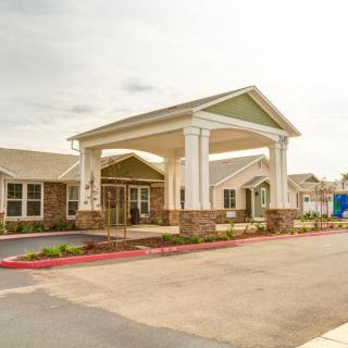 A modern building entrance with a portico and surrounding parking area.