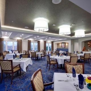 An elegant restaurant dining room with neatly set tables and chairs under warm lighting.