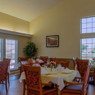 A cozy dining area with neatly arranged tables and chairs, featuring large windows and elegant decor.