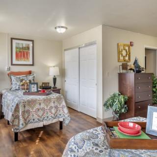 A cozy bedroom with two beds, decorated with patterned bedding and featuring wooden floors.