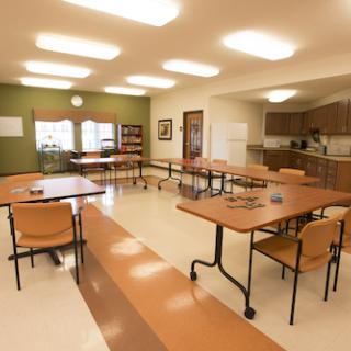 A spacious community room with tables and chairs arranged for a meeting or group activity.