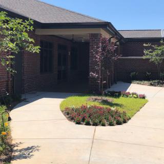 A well-landscaped entrance of a brick building with a tidy sidewalk and garden.