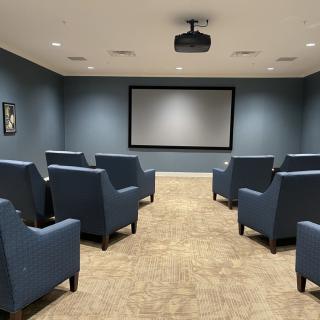 A cozy home theater setup with multiple chairs facing a large screen.