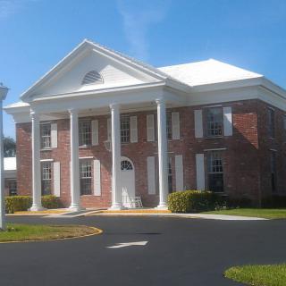 A classic-style brick building with large white columns and a triangular pediment.