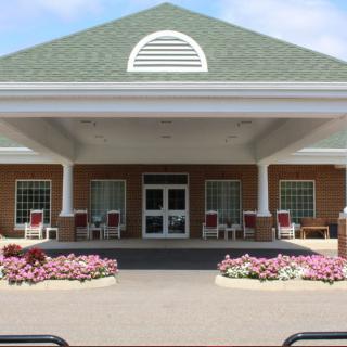 A spacious entrance with a covered porch and flower beds.