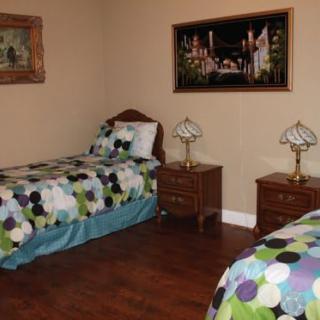 A cozy bedroom with two twin beds featuring colorful polka dot bedding, flanked by wooden nightstands with lamps, and adorned with framed wall art.