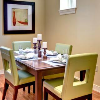 A modern dining room set with green chairs and a wooden table, accented by candles and wall art.