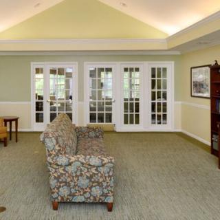 A cozy living room with floral sofas, French doors, and a bookshelf.