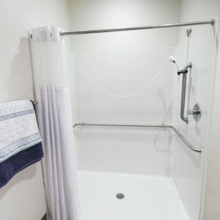 A clean and modern bathroom shower with a curtain and towel.
