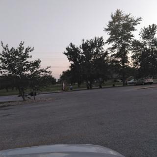 A tranquil evening view of a parking lot surrounded by trees.